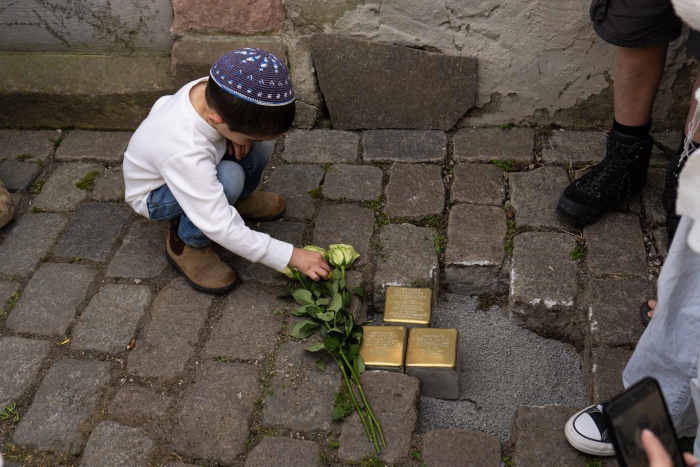 Kind legt Blumen auf Stolpersteine
