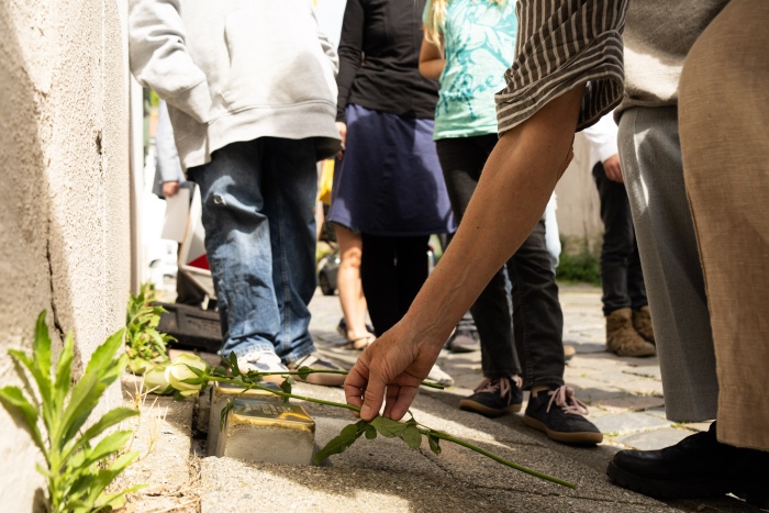 Person legt Blumen auf Stolpersteine