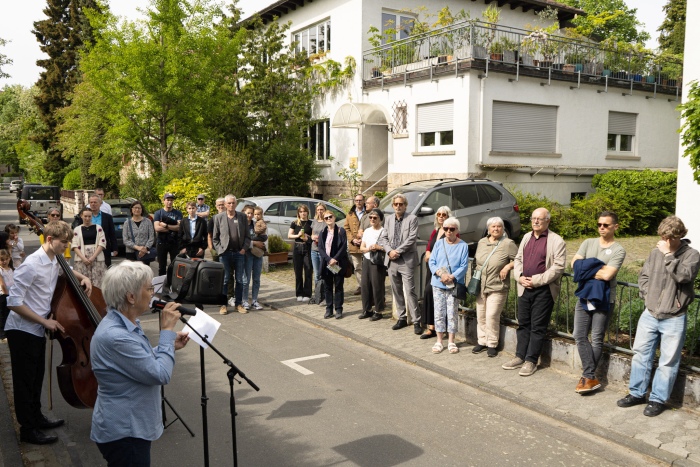 Frau redet am Mikrofon vor Menschengruppe